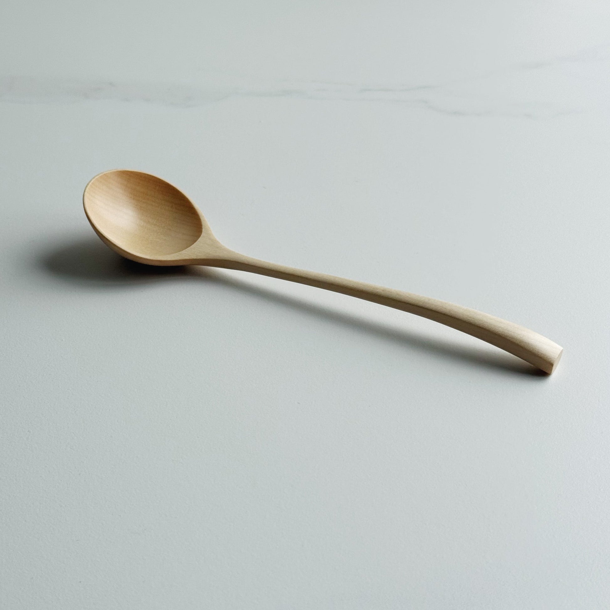 Angled eating spoon in sycamore on a light background