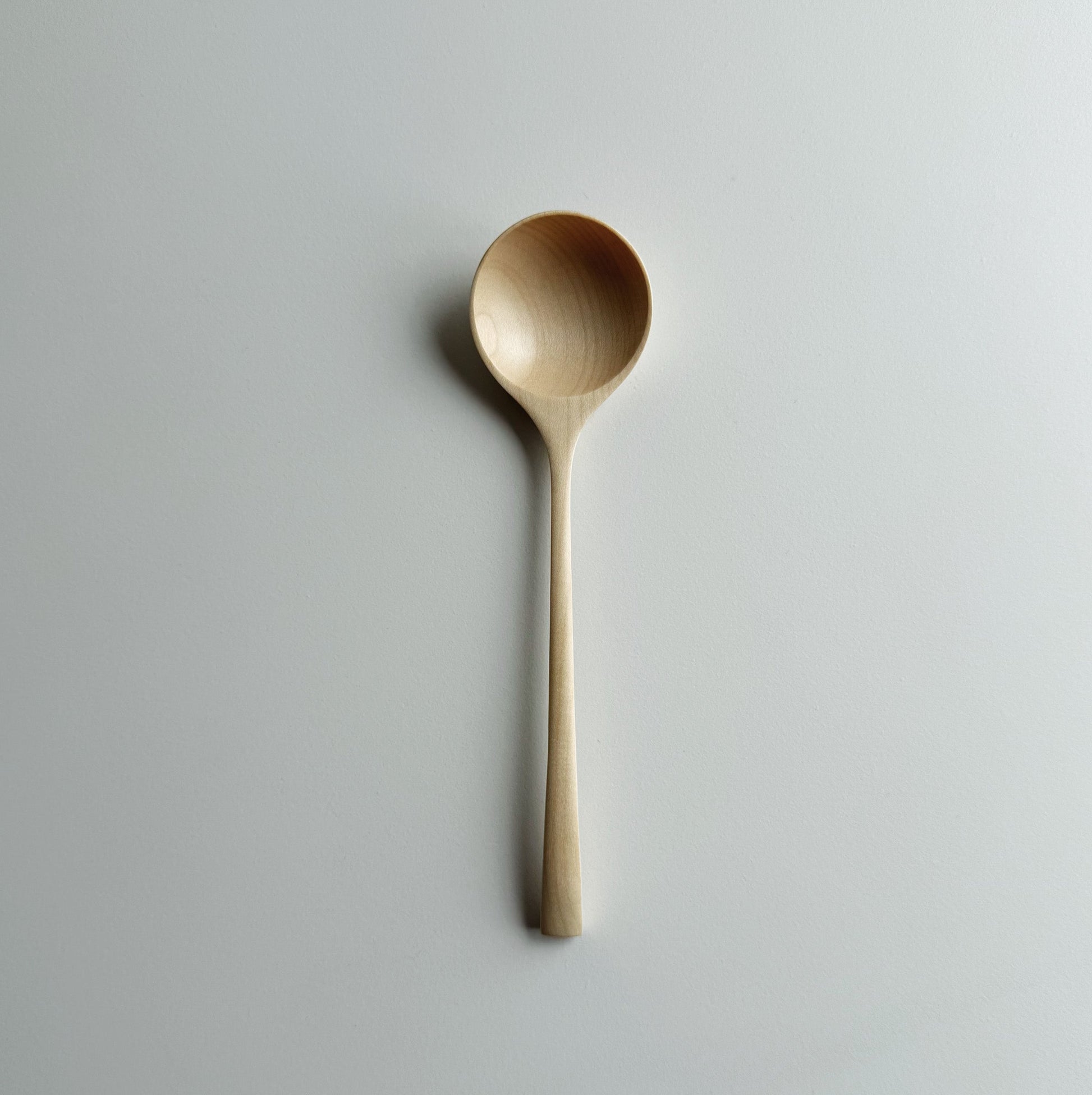 Angled eating spoon in sycamore on a light background