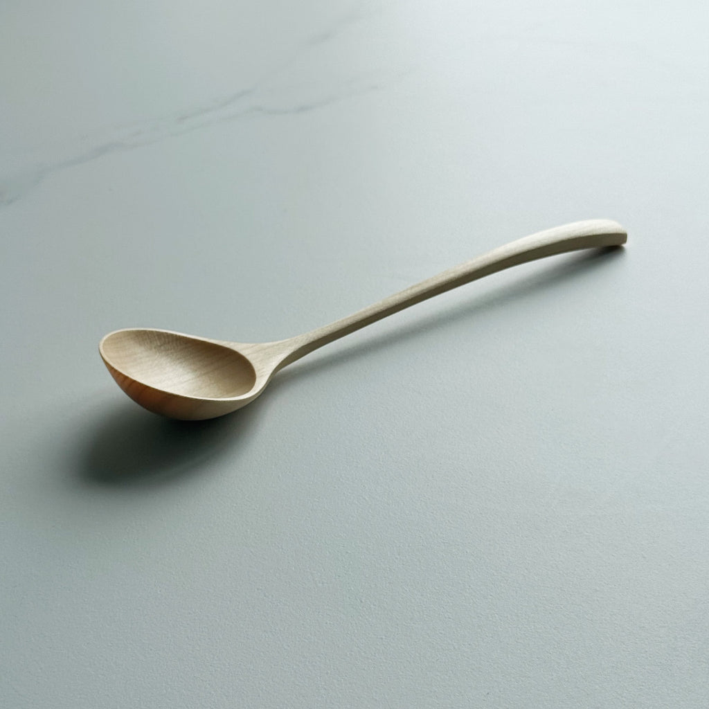 Angled eating spoon in sycamore on a light background