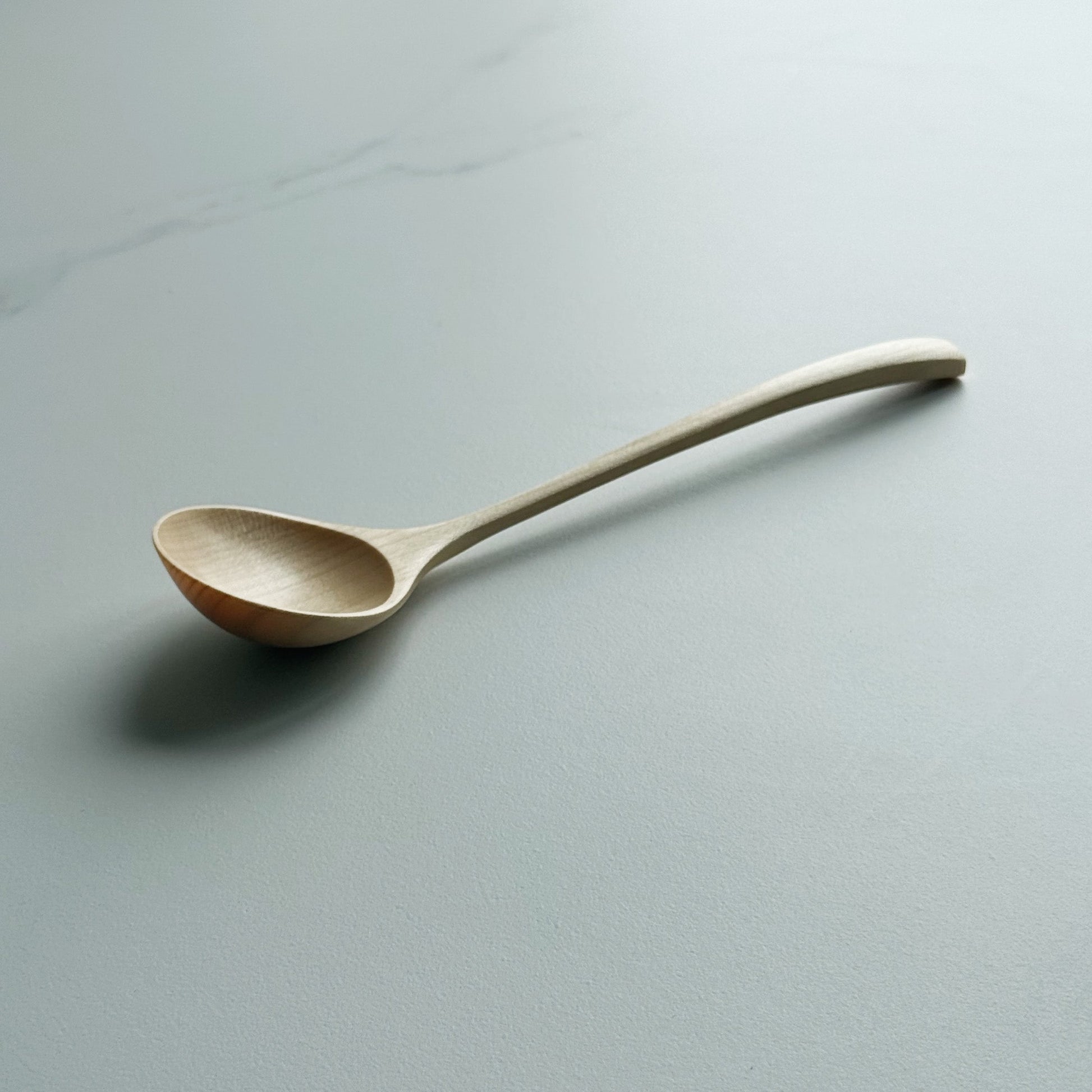 Angled eating spoon in sycamore on a light background