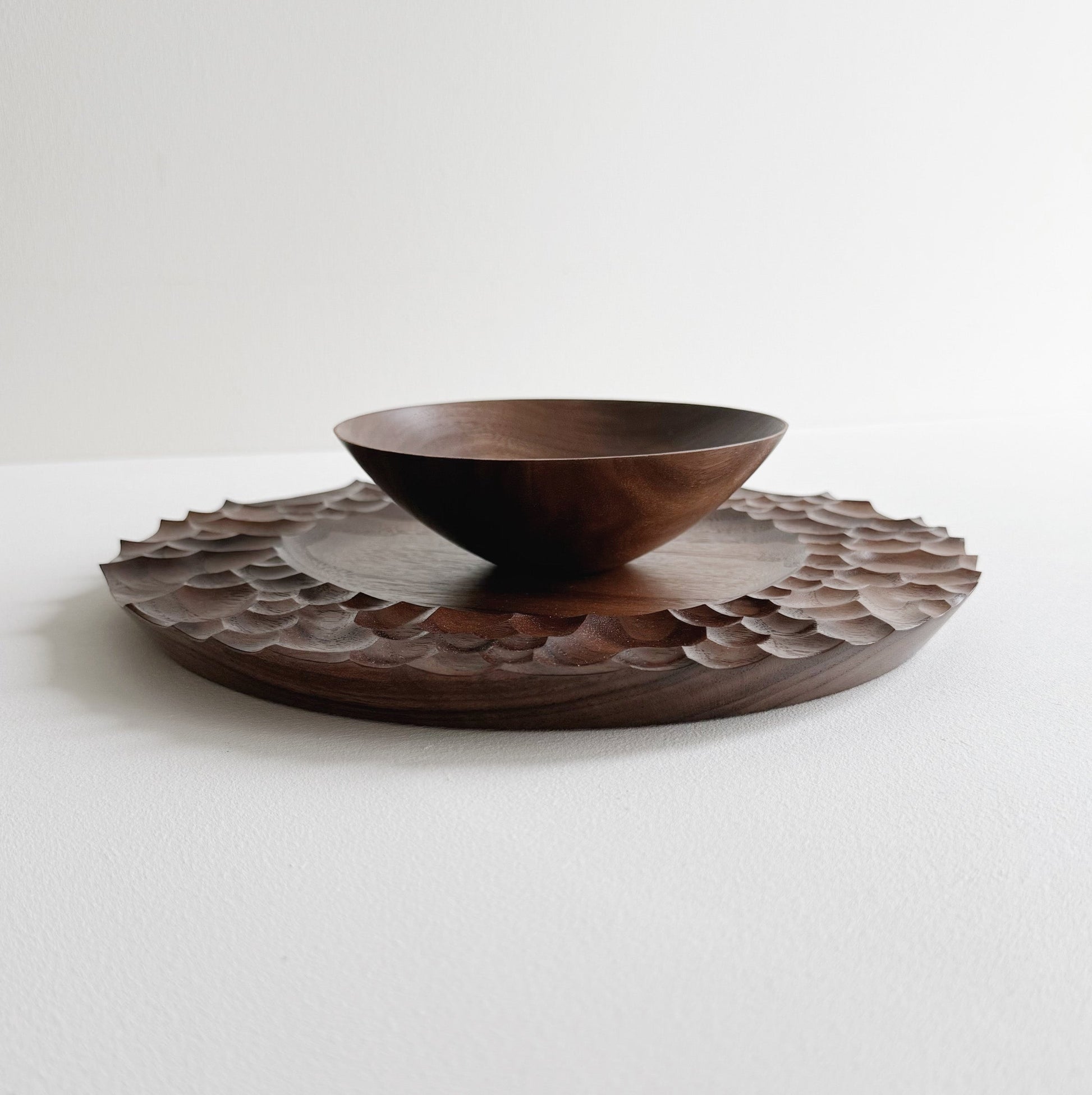 Biome plate and round palm bowl in tanned walnut on a light background