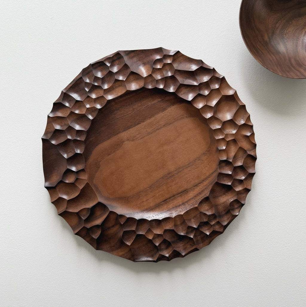 Biome plate and round palm bowl in tanned walnut on a light background