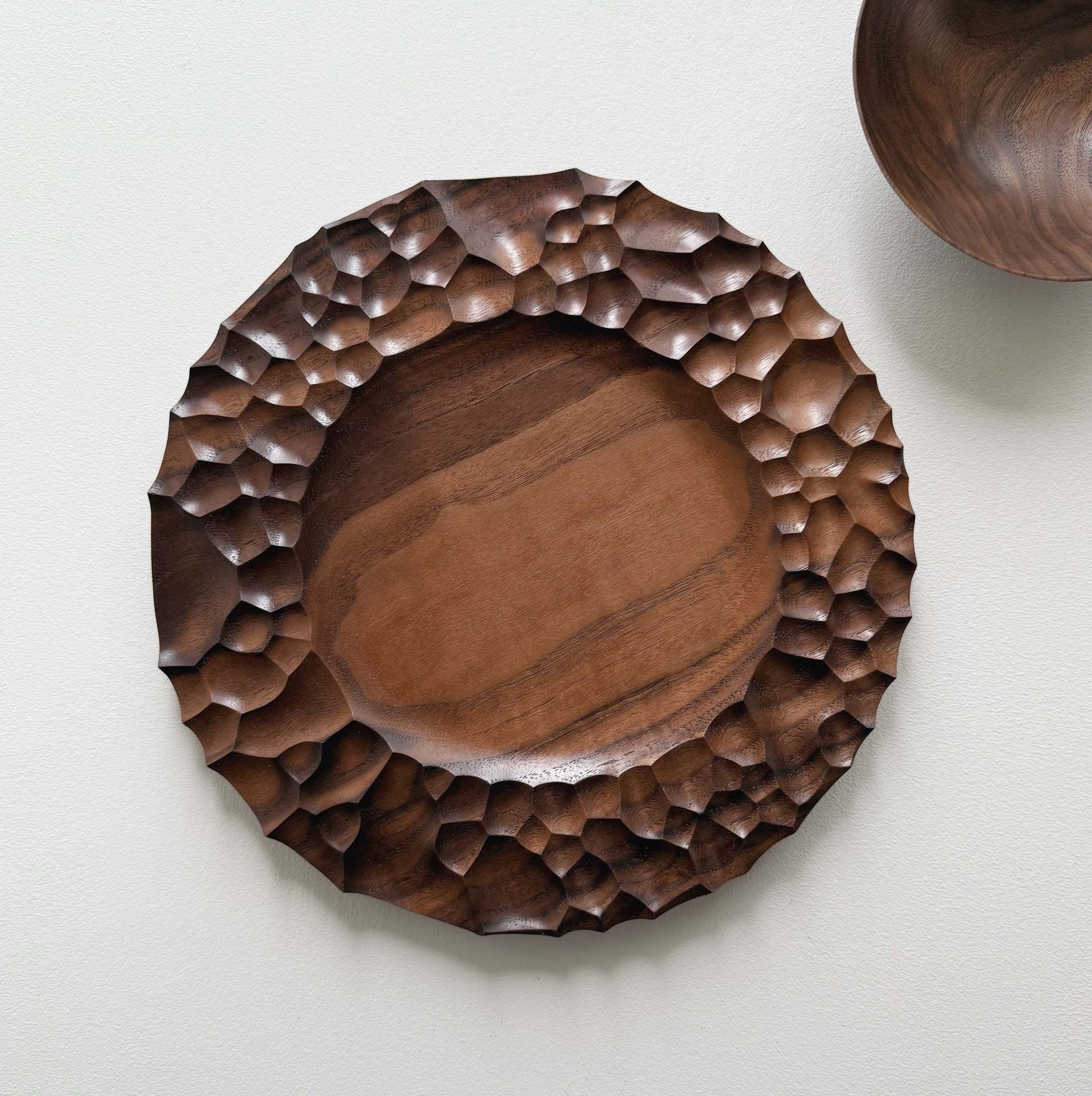 Biome plate and round palm bowl in tanned walnut on a light background