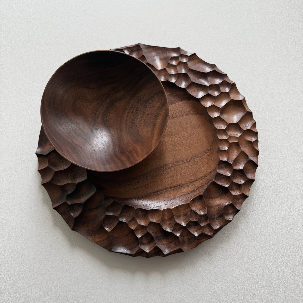 Biome plate and round palm bowl in tanned walnut on a light background