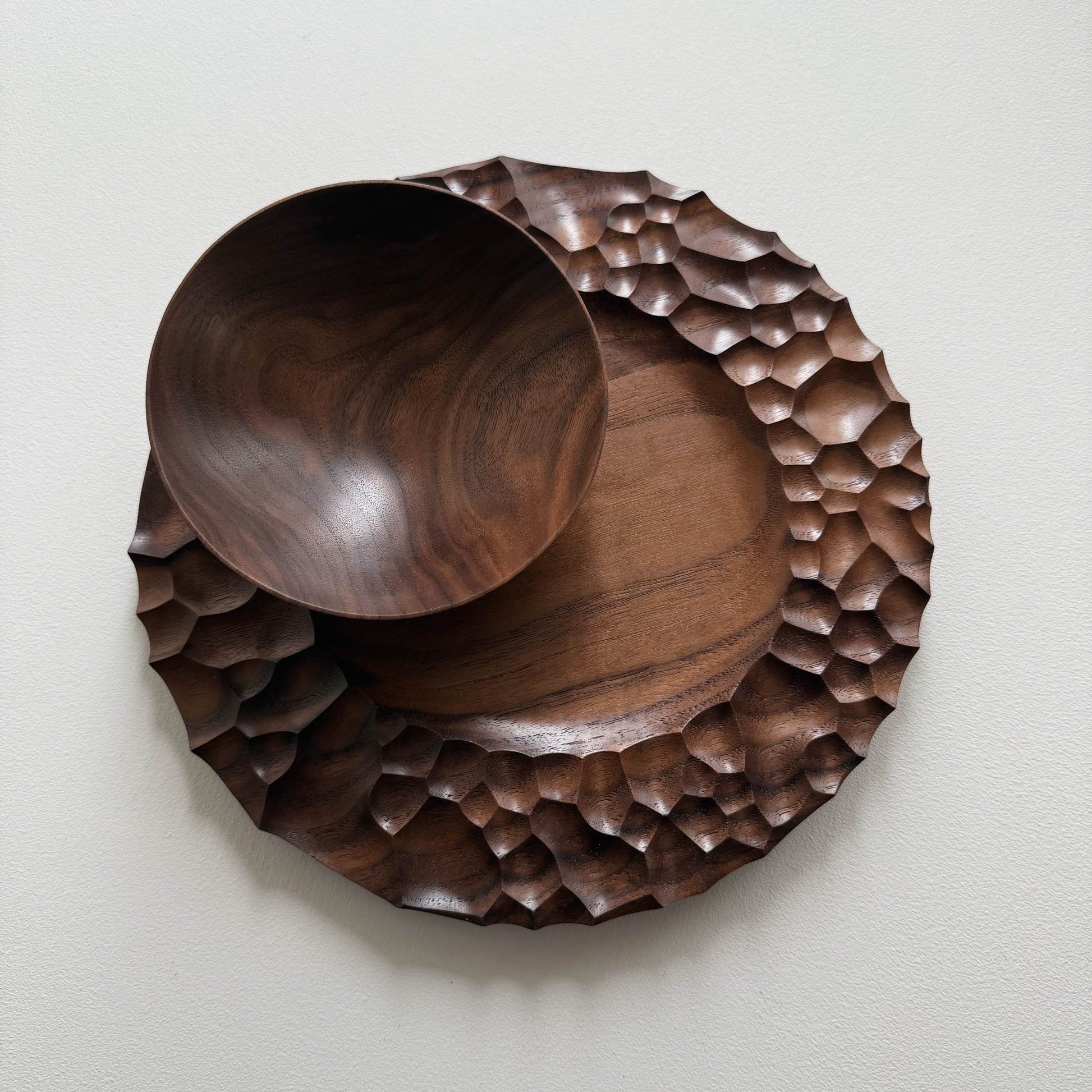 Biome plate and round palm bowl in tanned walnut on a light background