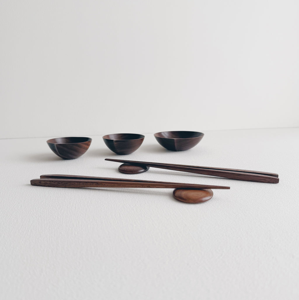 Set of walnut bowls and chopsticks on a white background