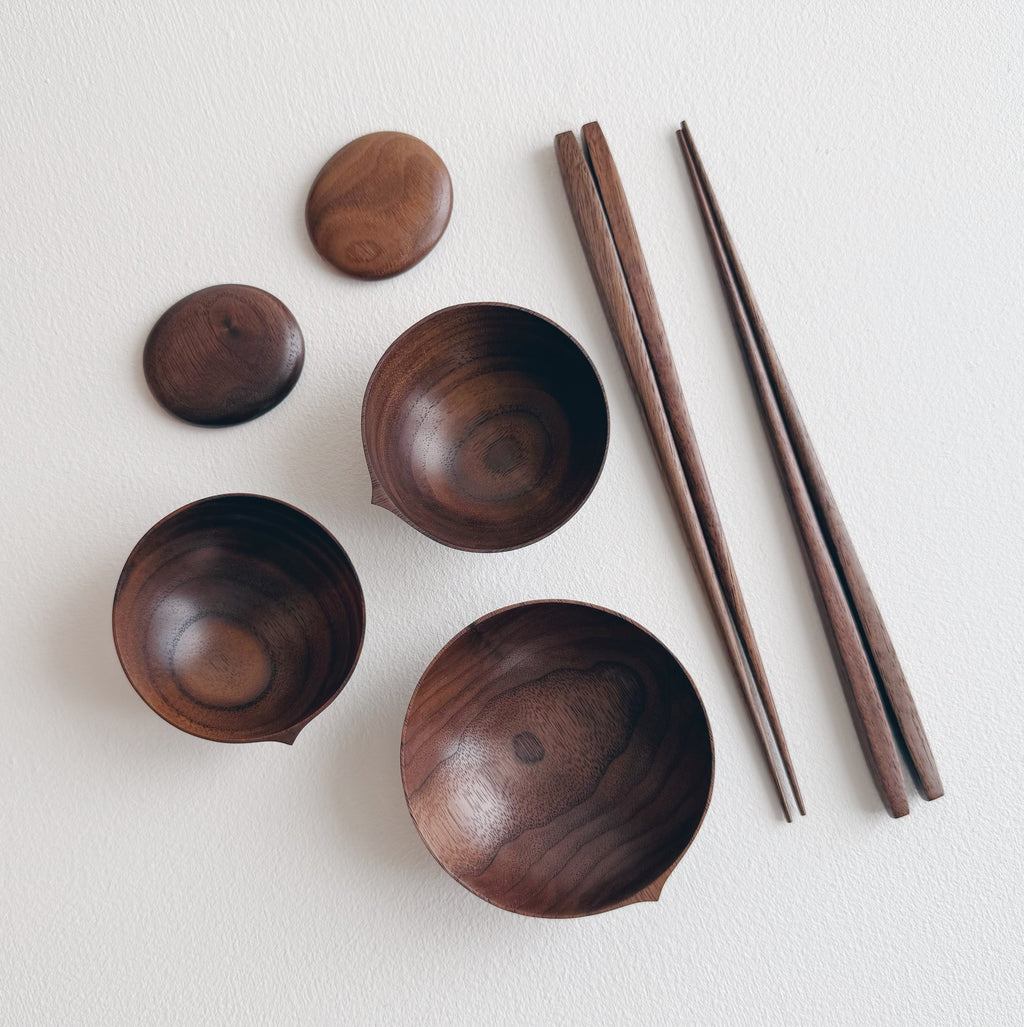 Set of walnut bowls and chopsticks on a white background