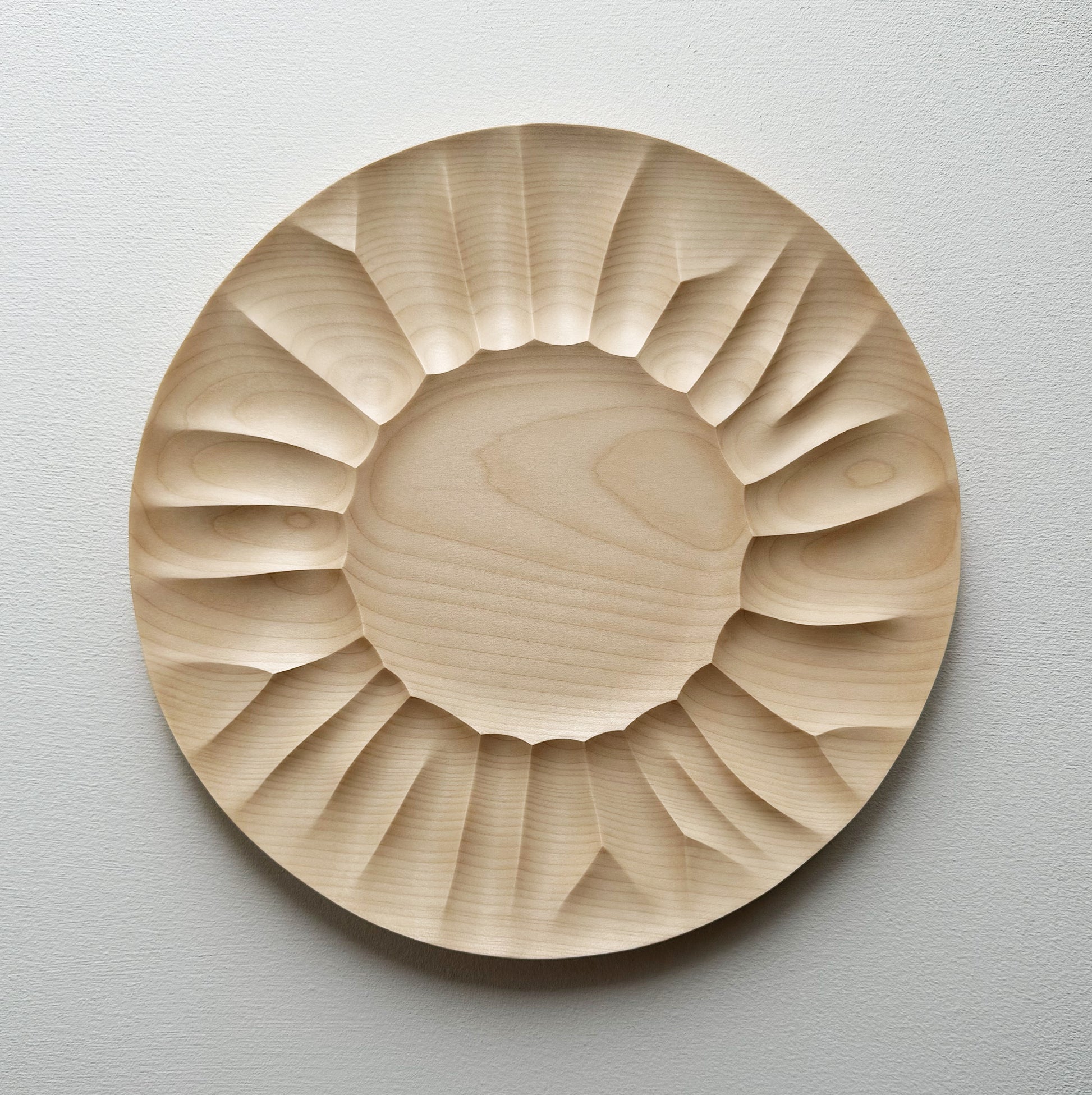 Sycamore wooden plate with a sculptural design on a white background