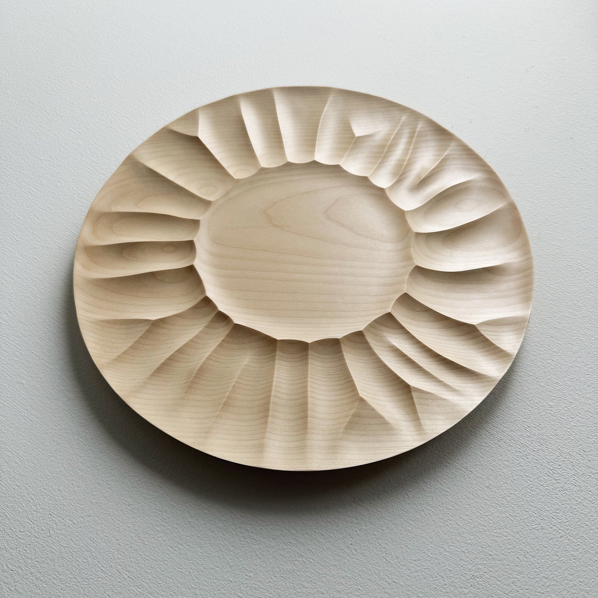 Sycamore wooden plate with a sculptural design on a white background