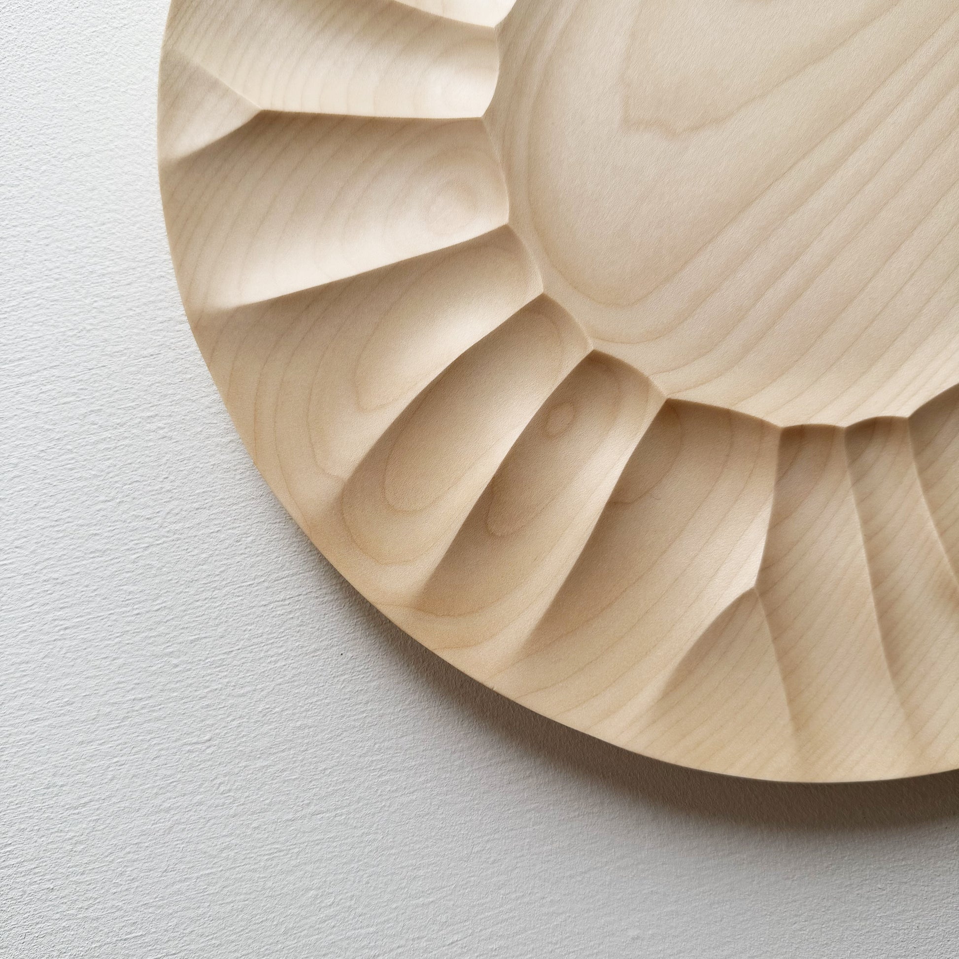 Close up of sycamore wooden plate with a sculptural design on a white background