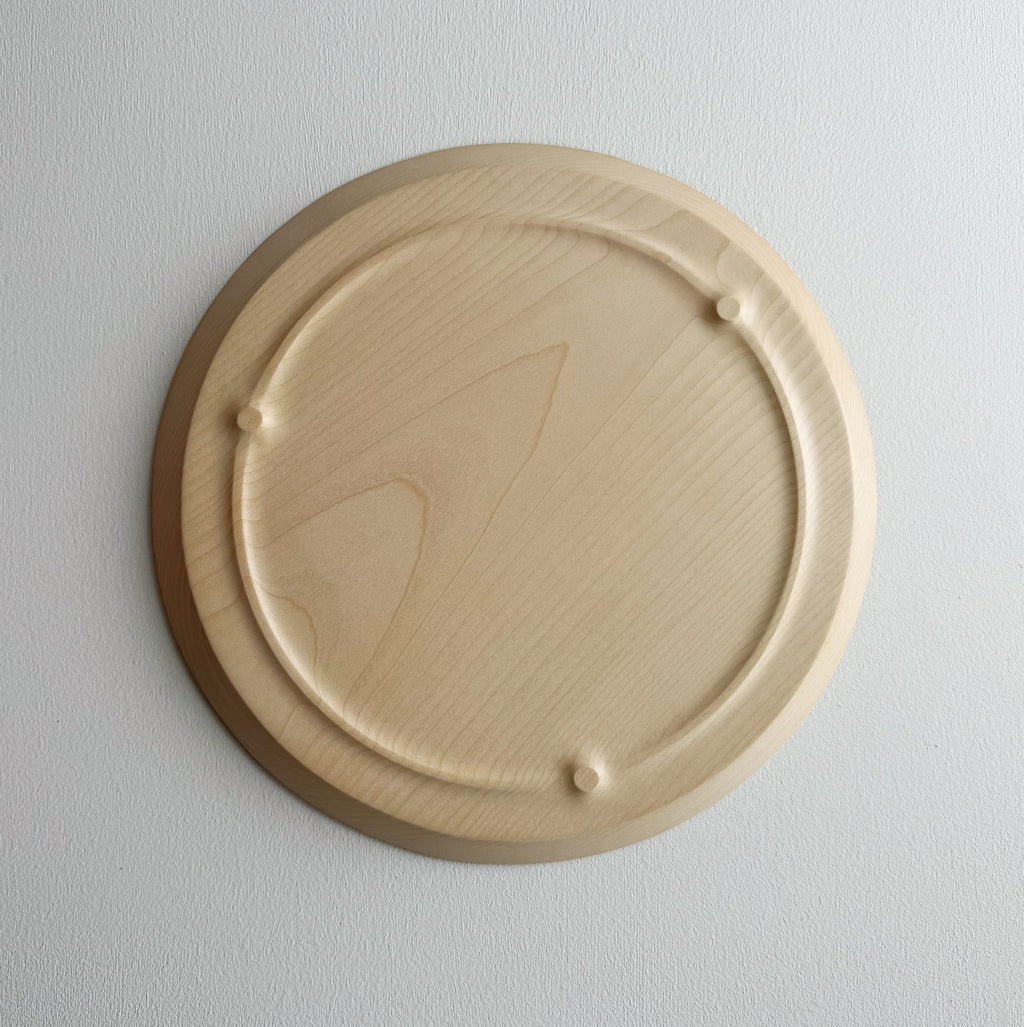 Underneath of sycamore wooden plate with a sculptural design on a white background
