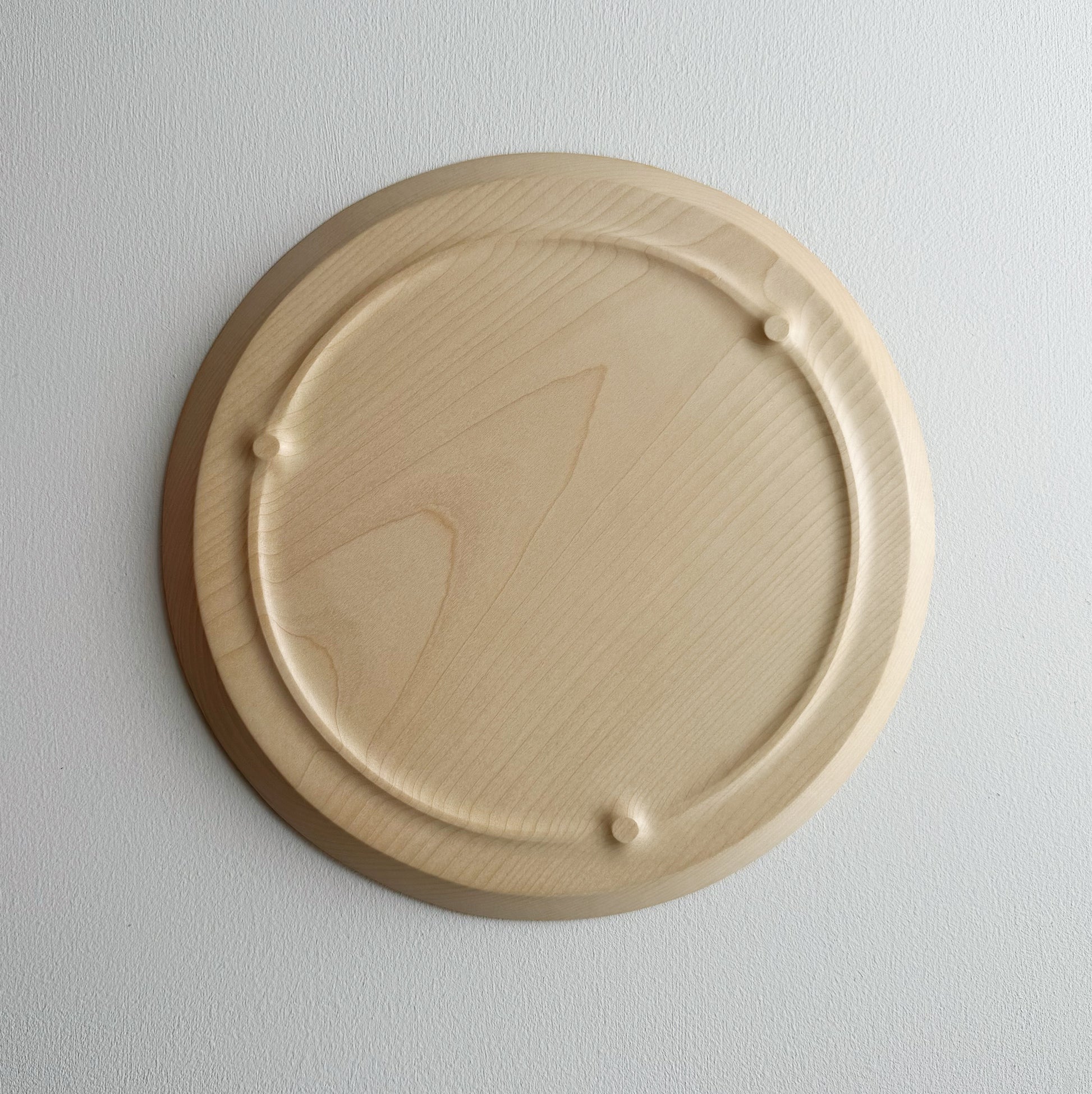 Underneath of sycamore wooden plate with a sculptural design on a white background