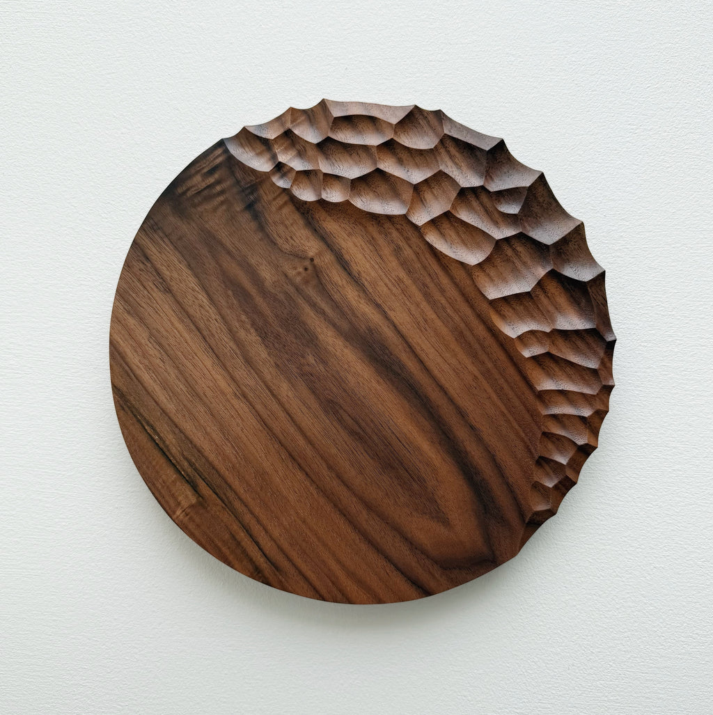 Walnut wooden plate with crater edge design on a white background