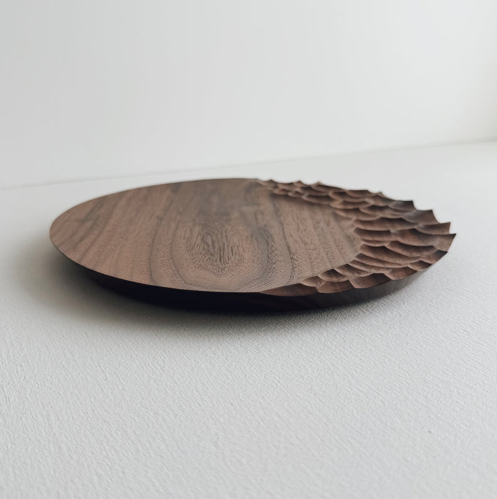 Walnut wooden plate with crater edge design on a white background