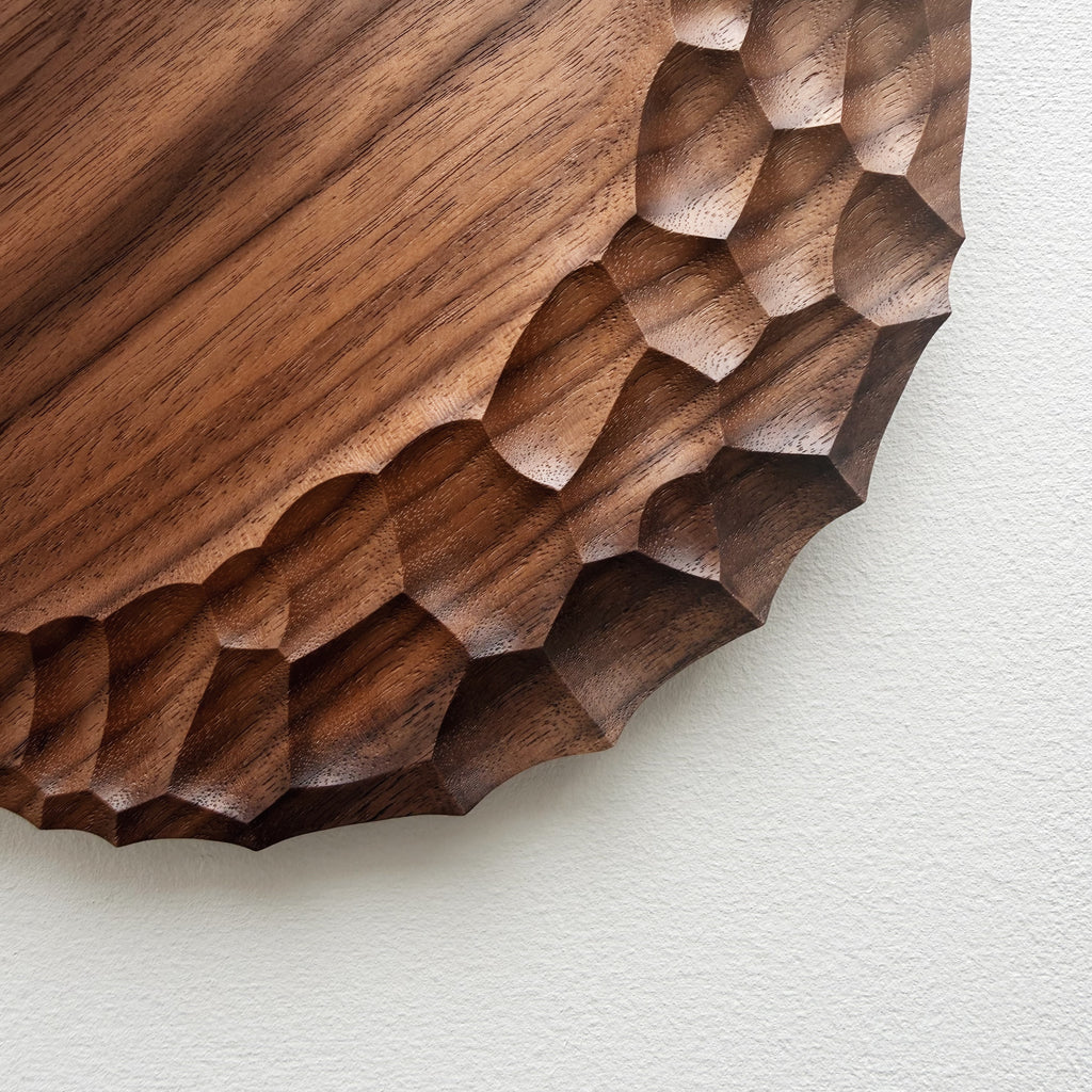 Close up of walnut wooden plate with crater edge design on a white background