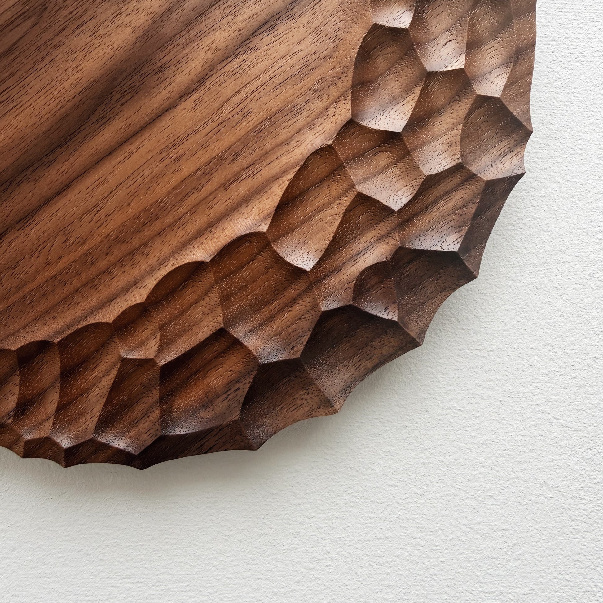 Close up of walnut wooden plate with crater edge design on a white background