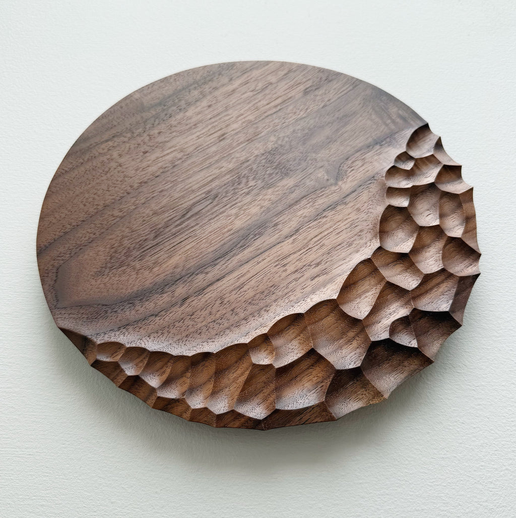 Walnut wooden plate with crater edge design on a white background