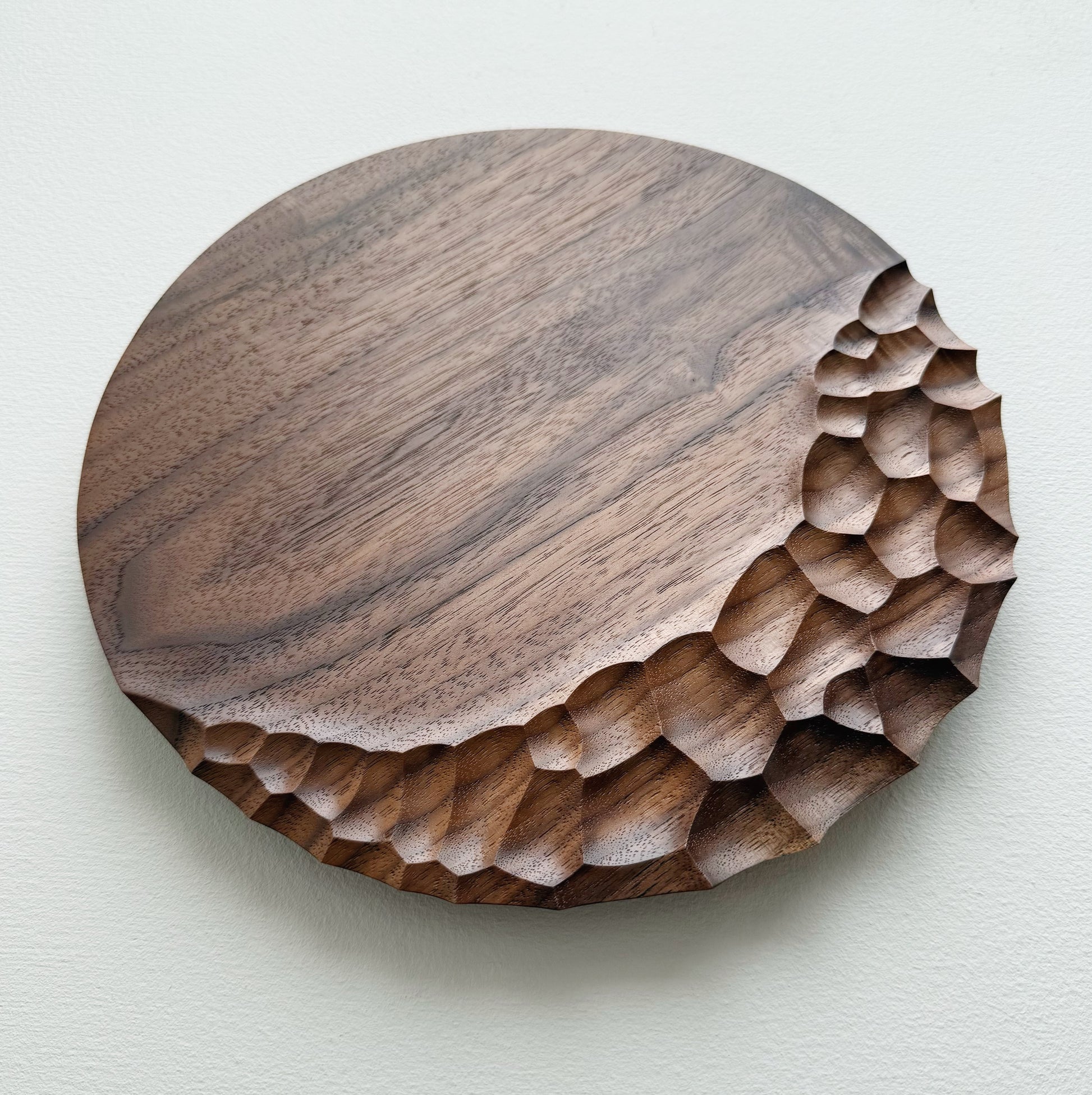 Walnut wooden plate with crater edge design on a white background