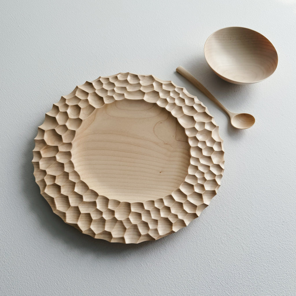 Sycamore wooden plate with craters design, bowl and eating spoon on a white background
