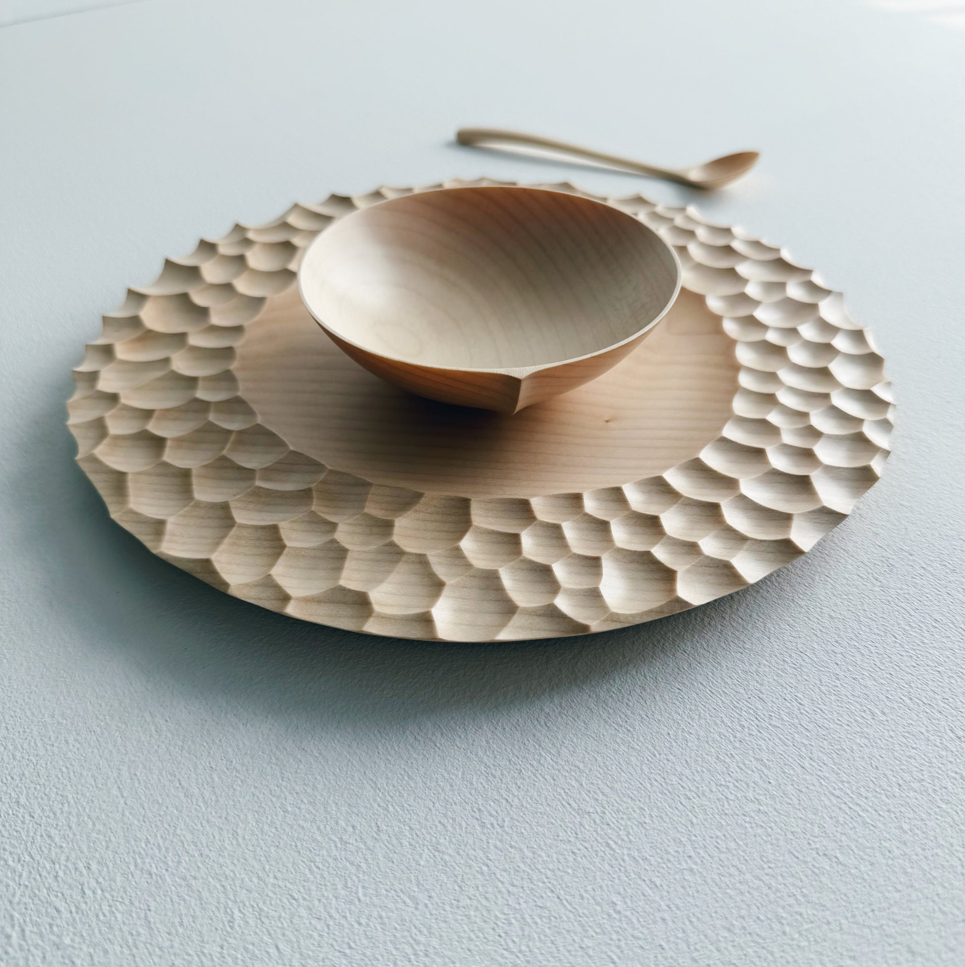 Sycamore wooden plate with craters design, bowl and eating spoon on a white background