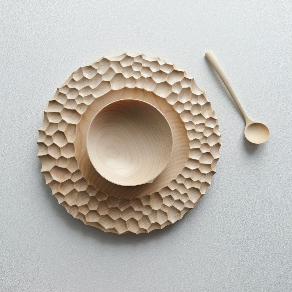 Sycamore wooden plate with craters design, bowl and eating spoon on a white background
