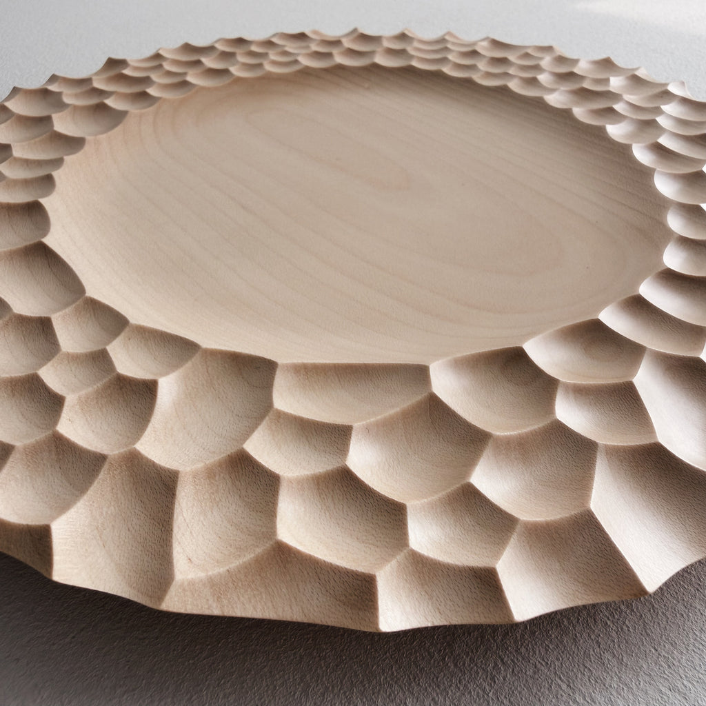 Close up of craters sycamore plate with sculptural design on a white background
