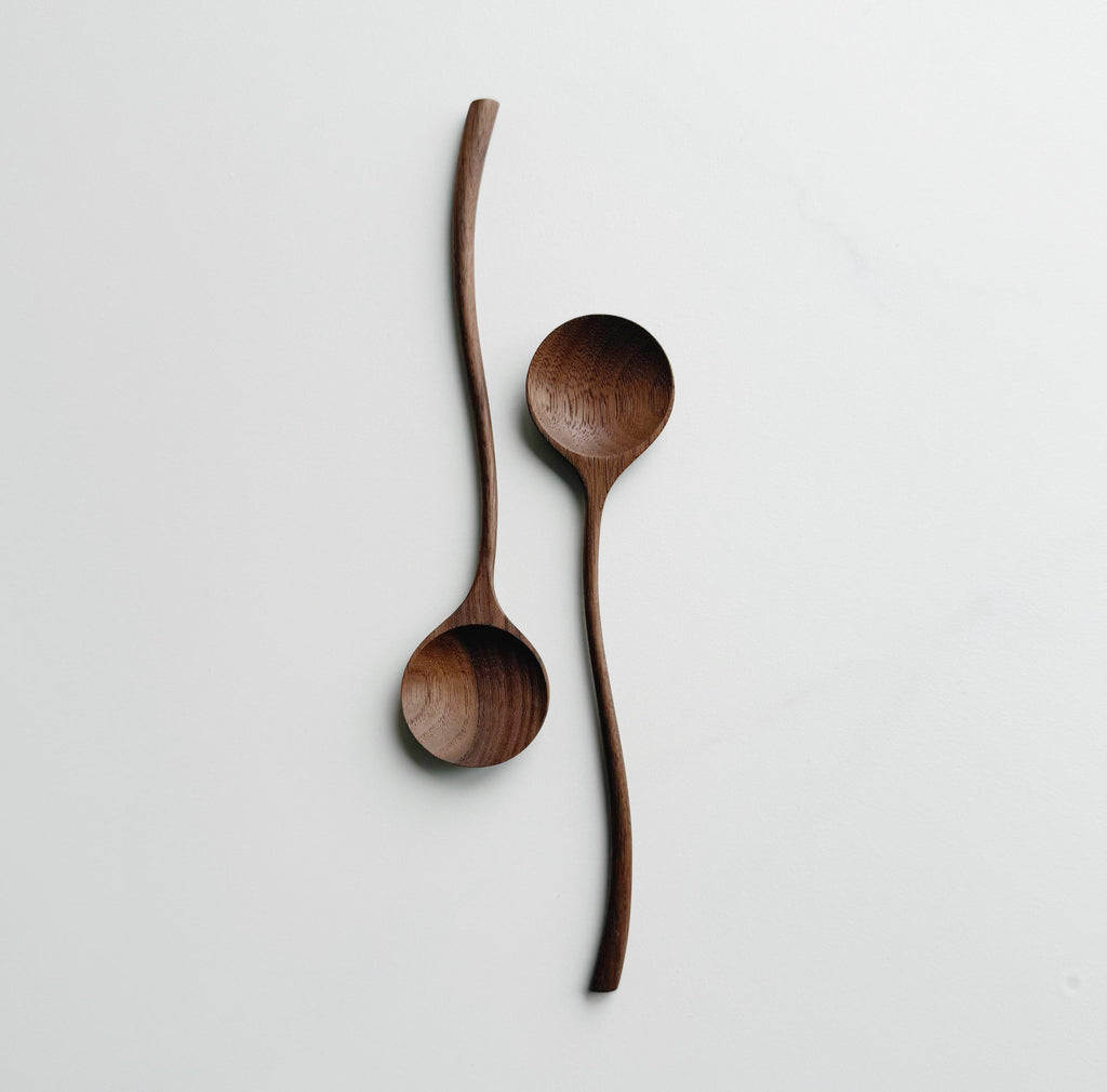 Two walnut curvy spoons on a light background