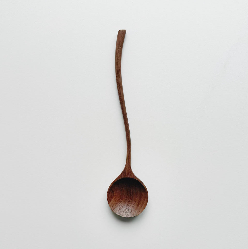 Two walnut curvy spoons on a light background