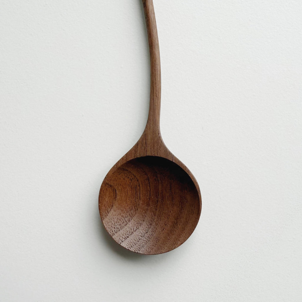 Two walnut curvy spoons on a light background