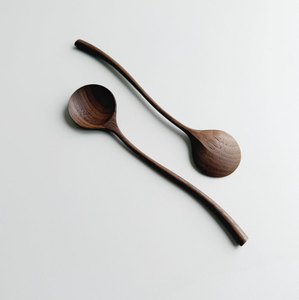 Two walnut curvy spoons on a light background