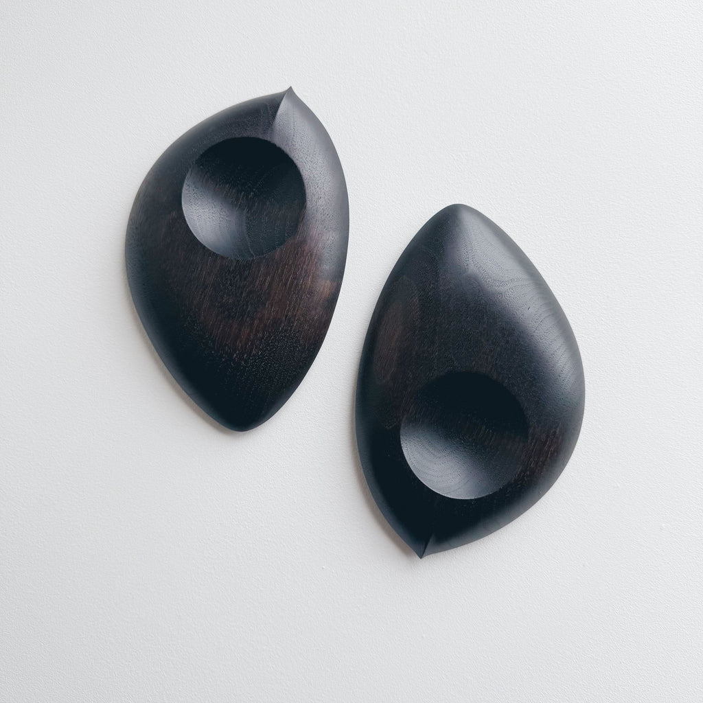 Pair of droplet dishes in ebonised walnut on a light background
