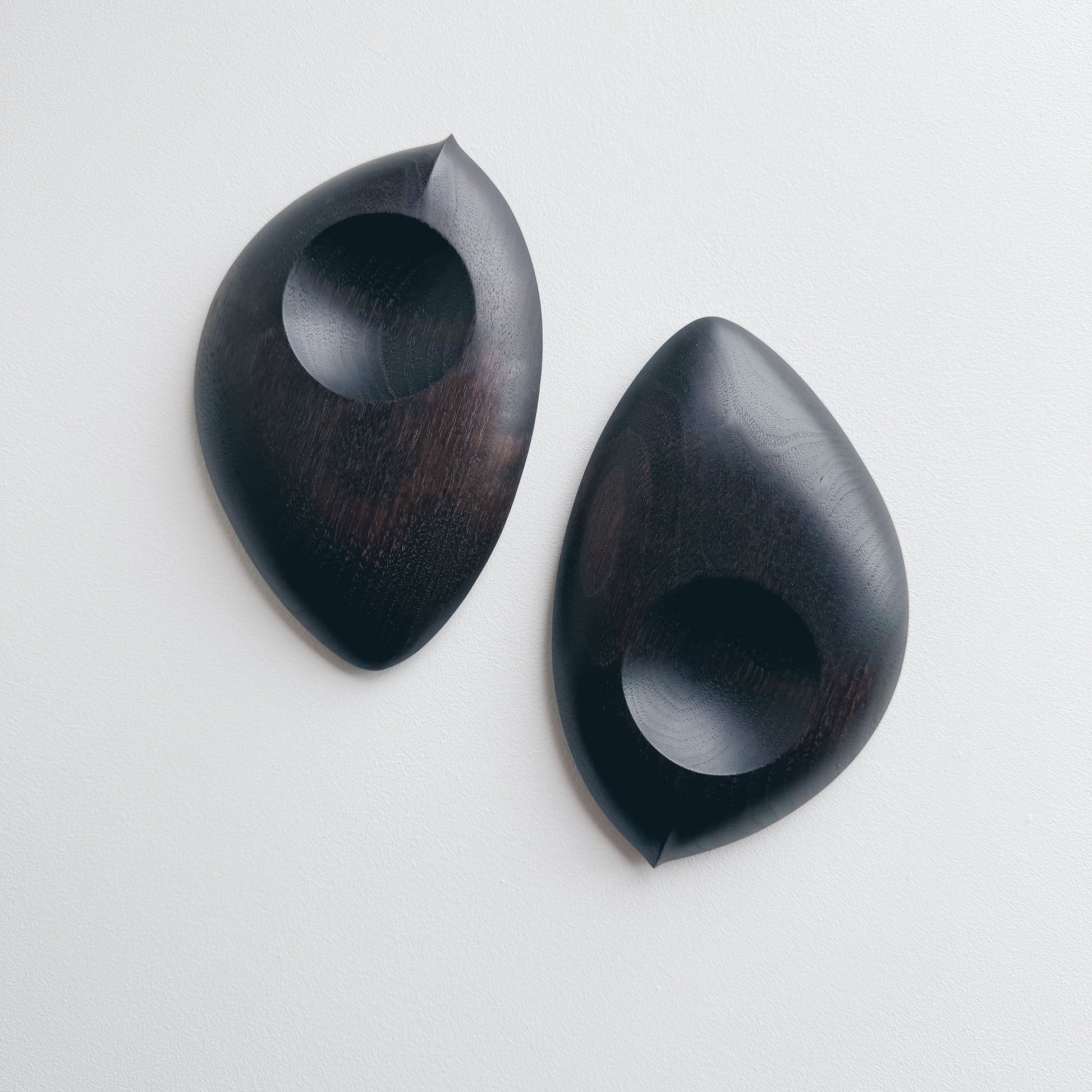 Pair of droplet dishes in ebonised walnut on a light background

