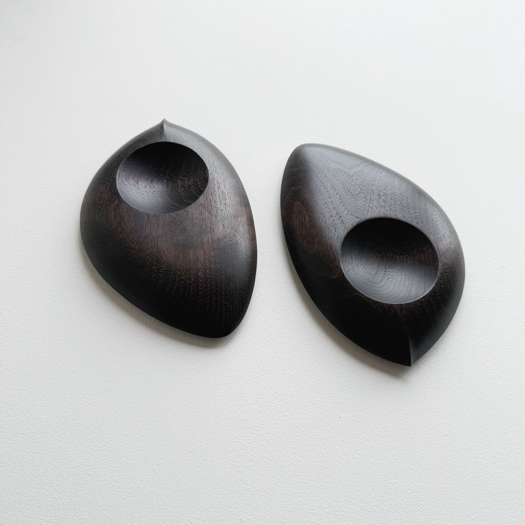 Pair of droplet dishes in ebonised walnut on a light background
