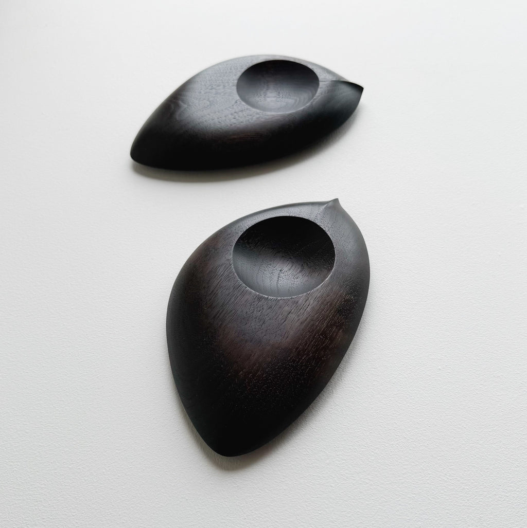 Pair of droplet dishes in ebonised walnut on a light background
