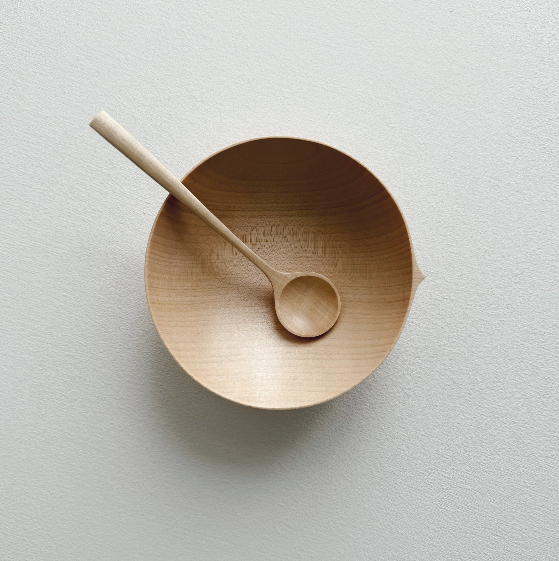 Eating bowl in sycamore with angled eating spoon on a white background
