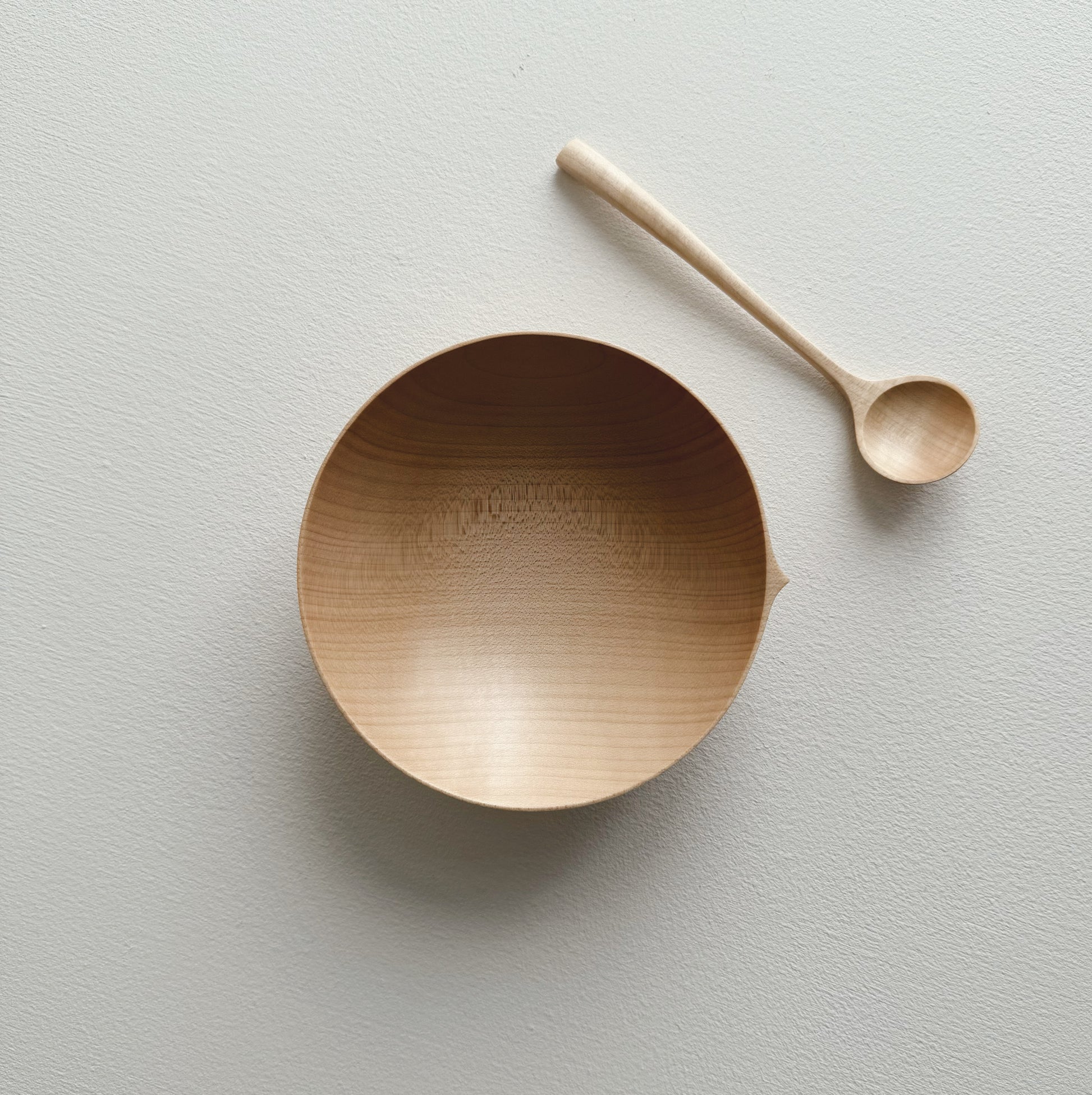 Eating bowl in sycamore with angled eating spoon on a white background
