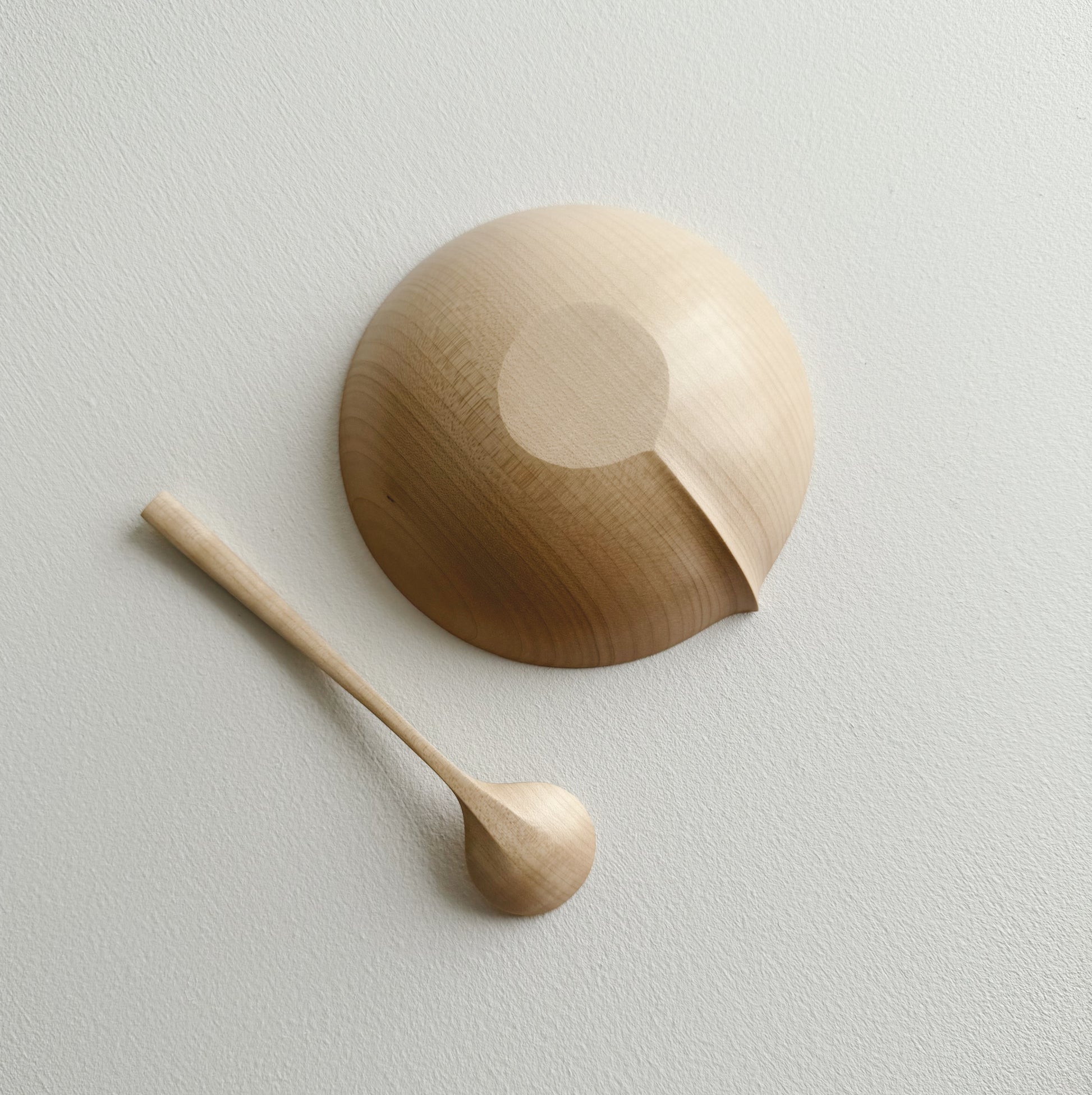 Eating bowl in sycamore with angled eating spoon on a white background
