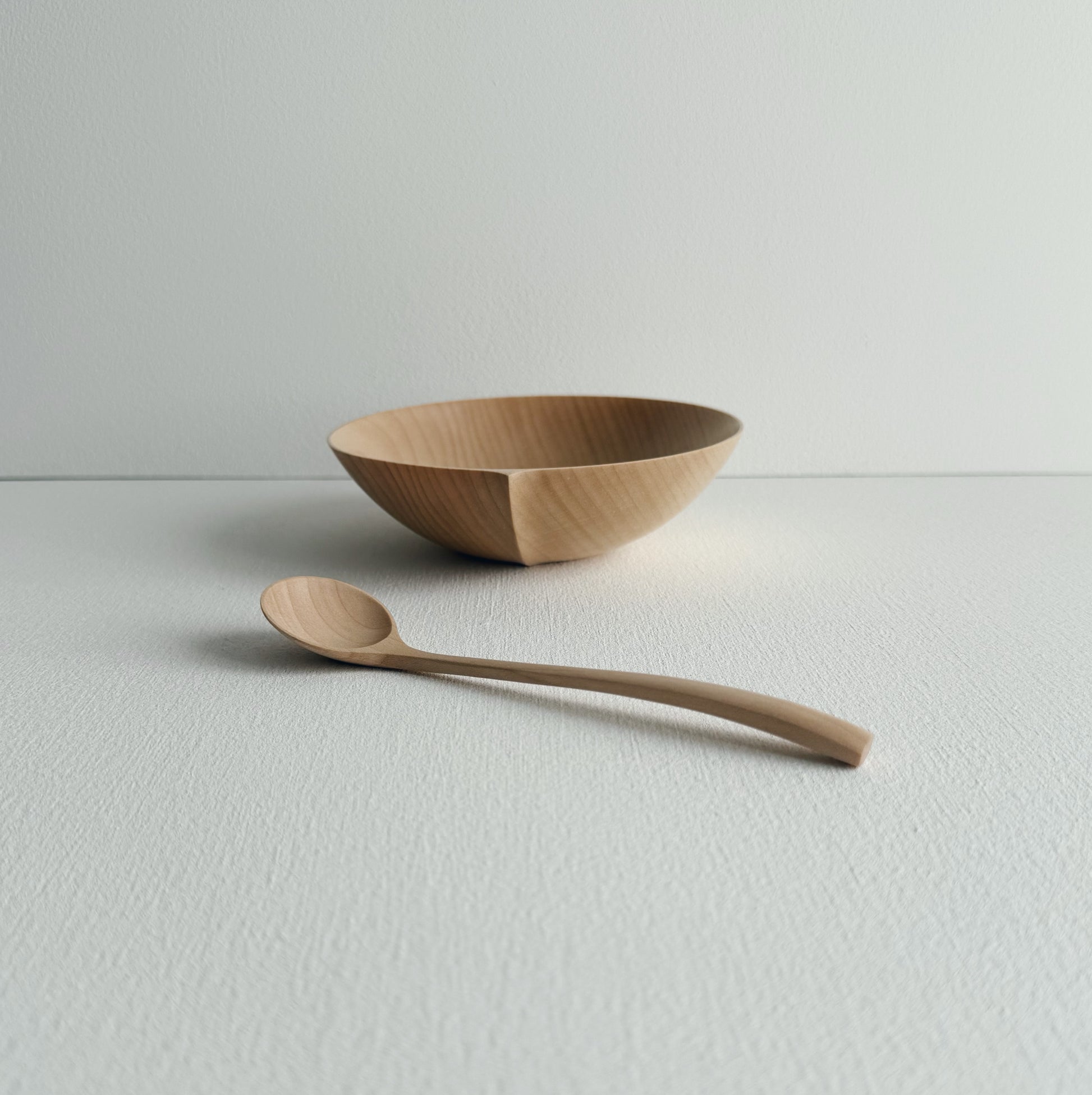 Eating bowl in sycamore with angled eating spoon on a white background
