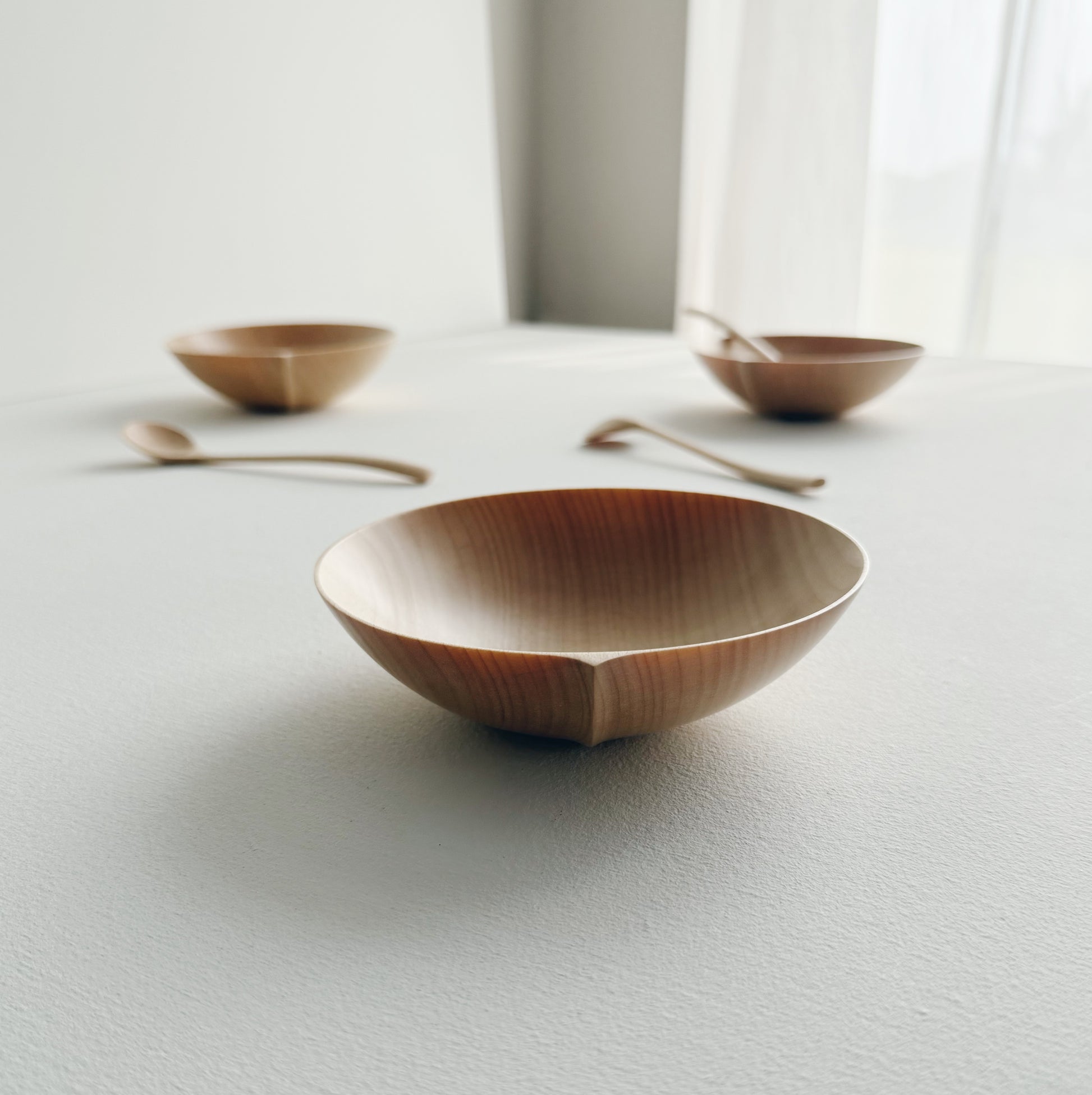 Eating bowl in sycamore with angled eating spoon on a white background
