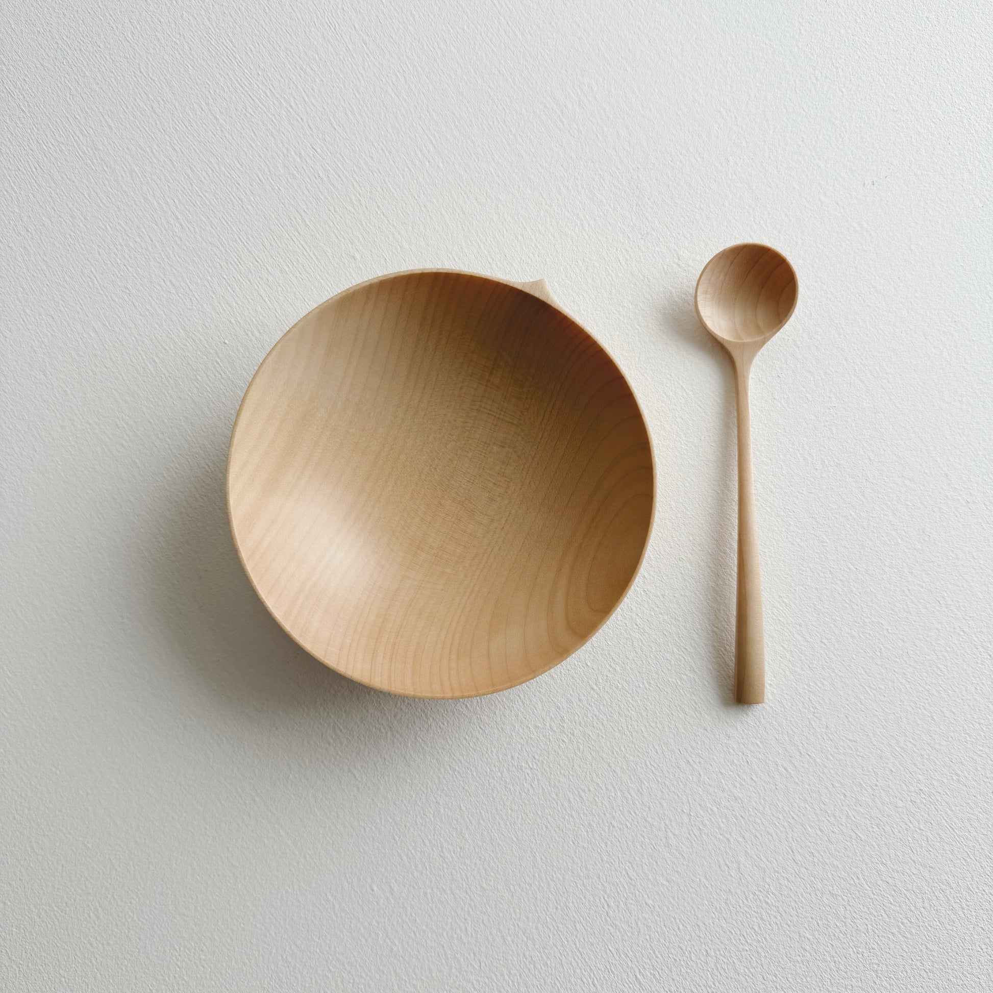 Eating bowl in sycamore with angled eating spoon on a white background
