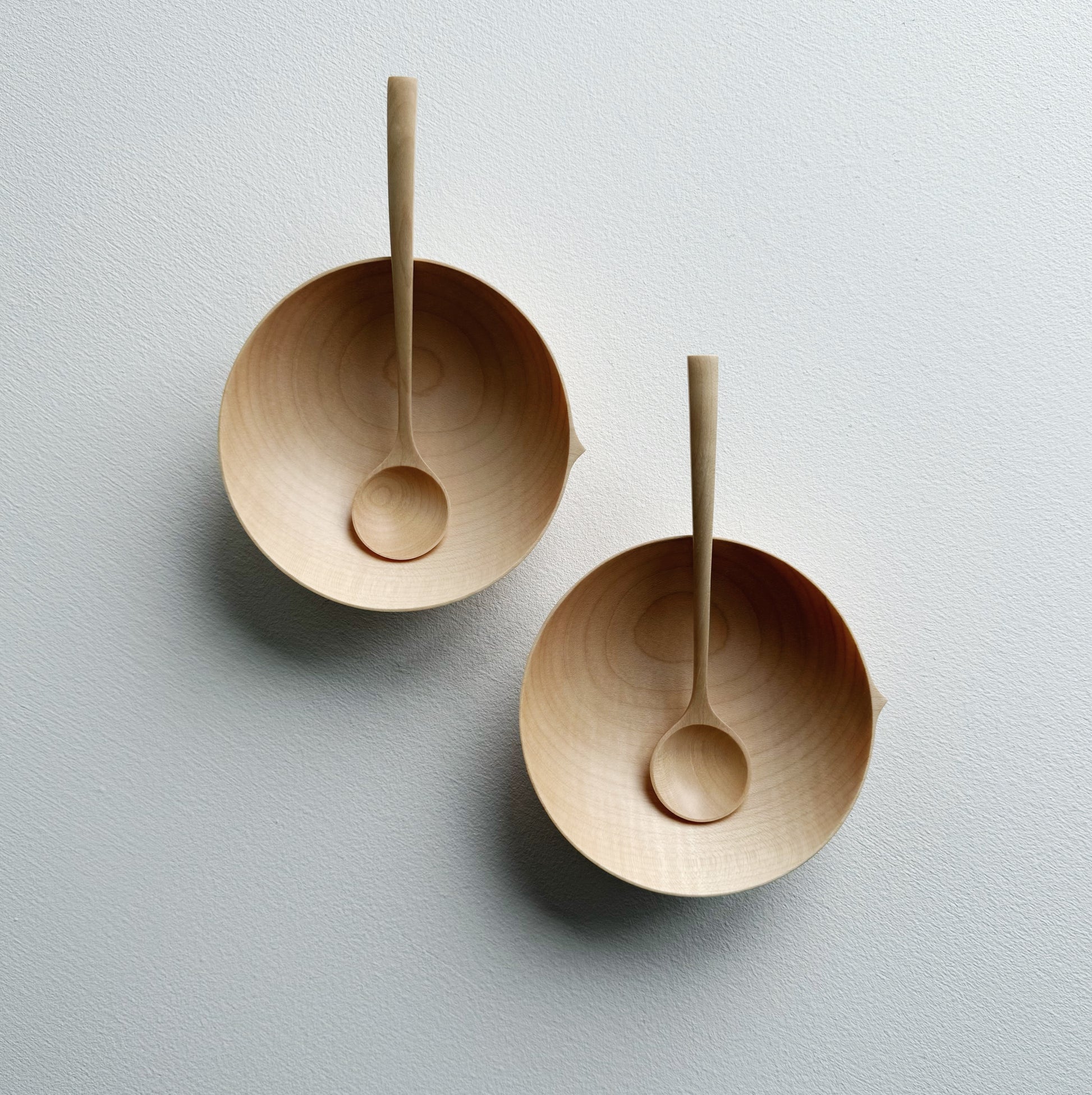 Two sycamore wooden bowls with sycamore spoons on a white background