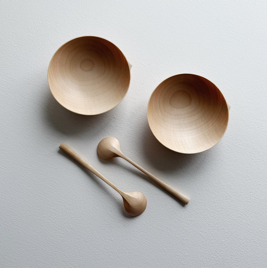 Two sycamore wooden bowls with sycamore spoons on a white background