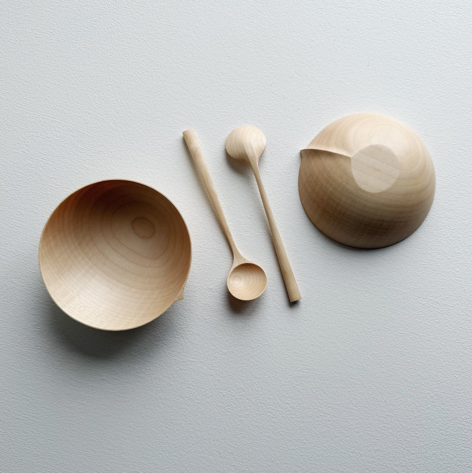 Two sycamore wooden bowls with sycamore spoons on a white background