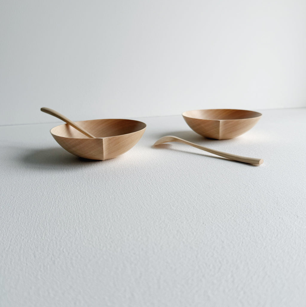Two sycamore wooden bowls with sycamore spoons on a white background