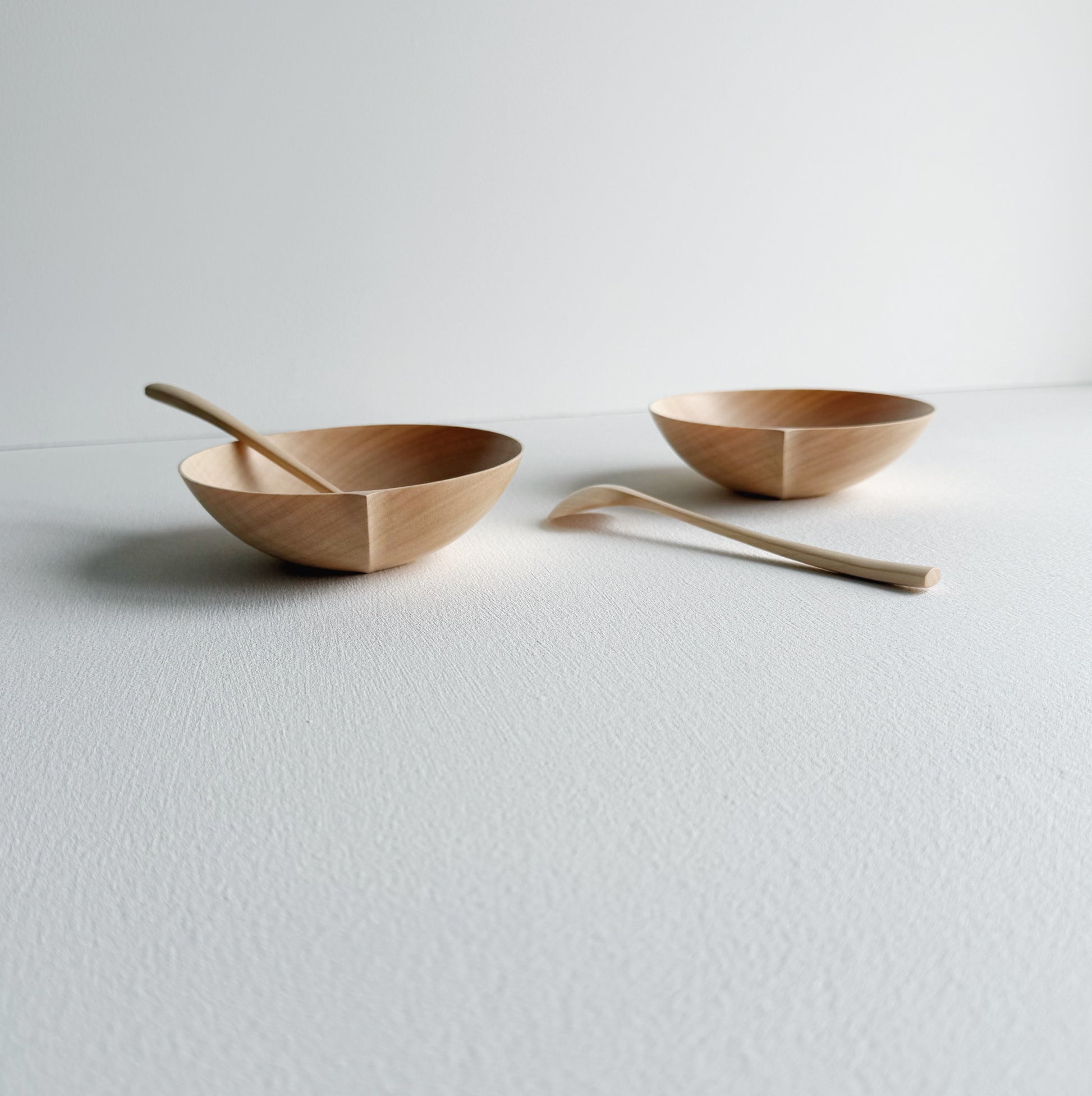 Two sycamore wooden bowls with sycamore spoons on a white background