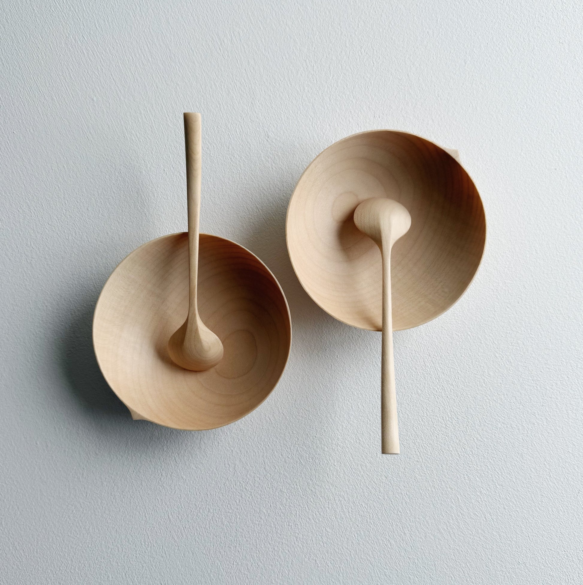 Two sycamore wooden bowls with sycamore spoons on a white background