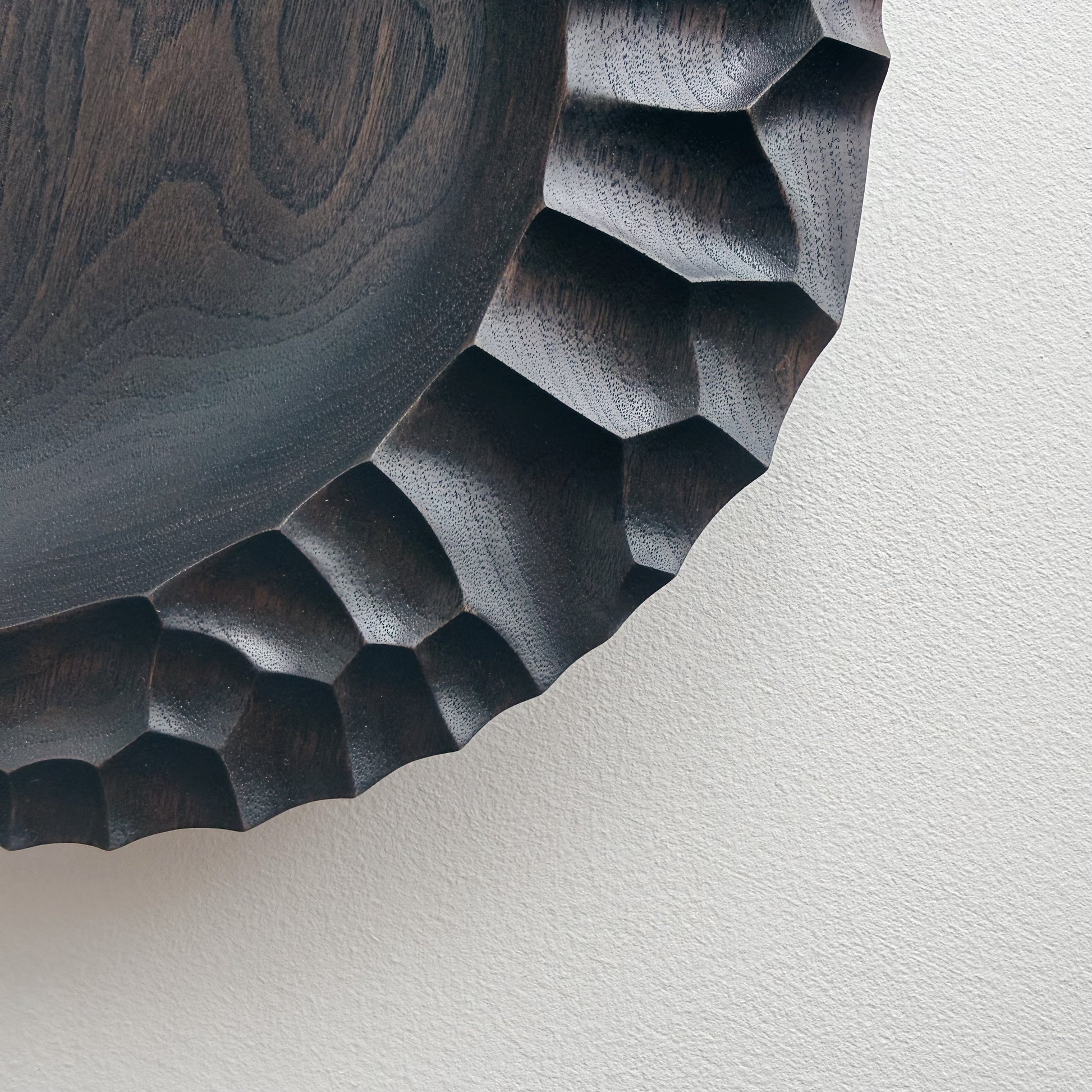Close up of ebonised walnut presentation board with sculptural design on a white background