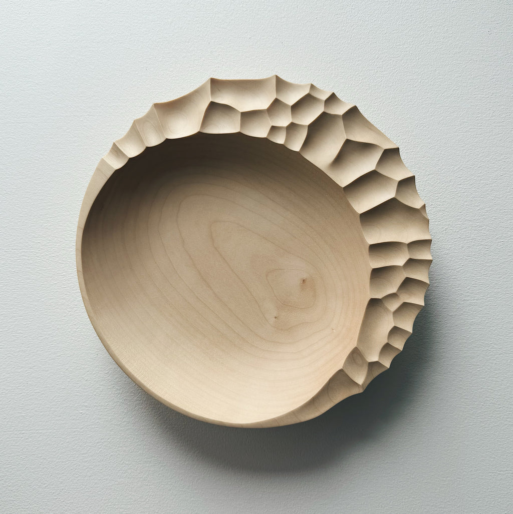 Wooden bowl with sculptural pattern on a white background
