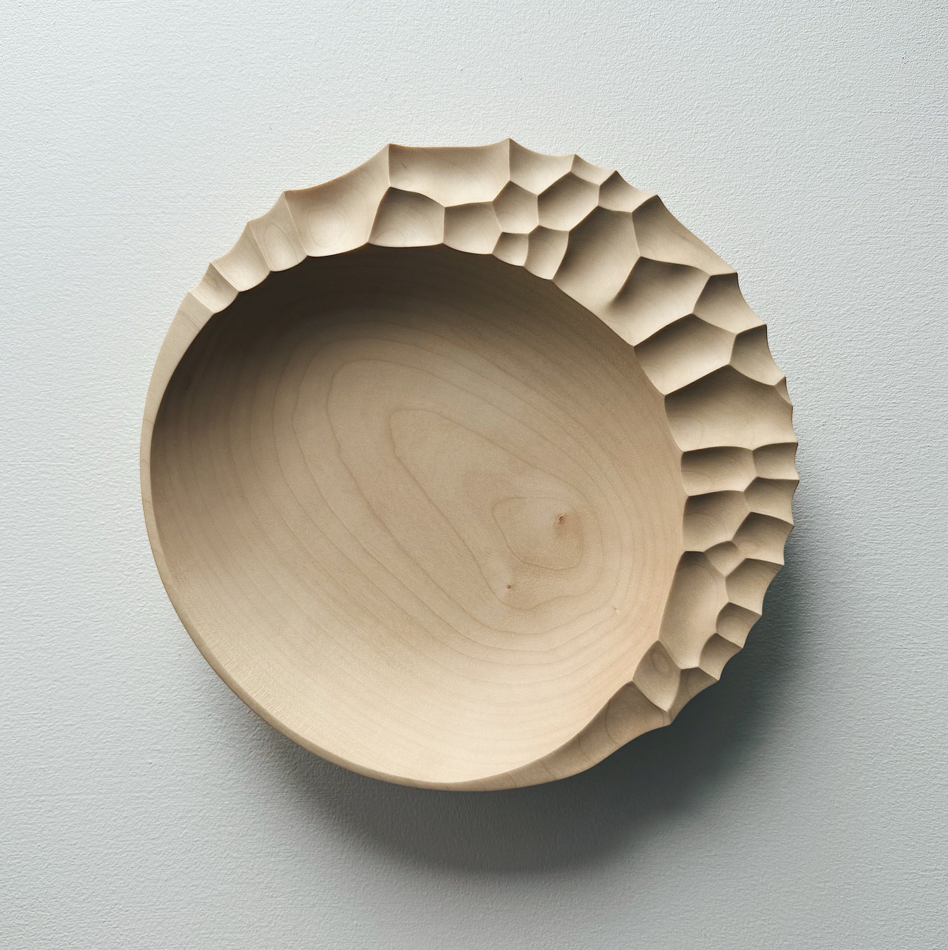 Wooden bowl with sculptural pattern on a white background
