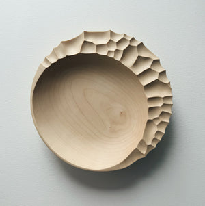 Wooden bowl with sculptural pattern on a white background